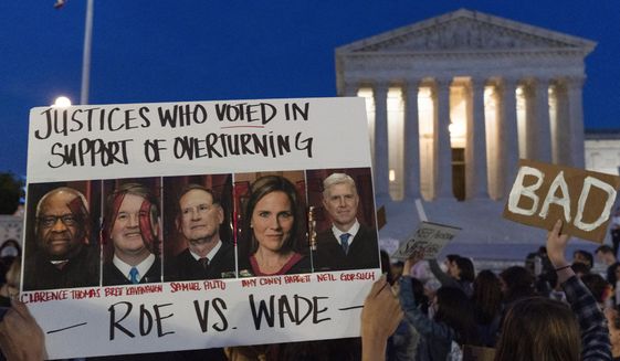 Nikki Tran of Washington, holds up a sign with pictures of Supreme Court Justices Thomas, Kavanaugh, Samuel Alito, Amy Coney Barrett, and Neil Gorsuch, as demonstrators protest outside of the U.S. Supreme Court, Tuesday, May 3, 2022, in Washington. Less than 24 hours after the unprecedented leak of the draft opinion that overturned Roe v. Wade, Chief Justice John G. Roberts Jr. ordered an investigation into the “egregious breach.” Since then? Silence. The Supreme Court won’t say whether it is still investigating. (AP Photo/Jacquelyn Martin, File)