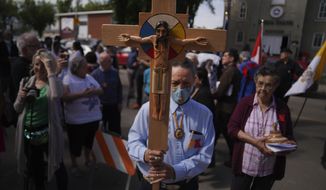 FILE - Elmer Waniandy raises the crucifix as he leads his fellow parishioner into the rededicated and newly renovated Sacred Heart Church of the First Peoples sanctuary, July 17, 2022, in Edmonton, Alberta. Pope Francis’ trip to Canada, which begins Sunday July 24, 2022, to apologize for the horrors of church-run Indigenous residential schools marks a radical rethink of the Catholic Church’s missionary legacy in the Americas, spurred on by the first American pope and the discovery of hundreds of unmarked graves at the school sites. (AP Photo/Jessie Wardarski, File)