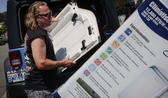 Brian Gadzuk, 56, clears out the trunk of his Jeep to make space for a new air conditioning unit in the parking lot of McLendon Hardware in Renton, Wash., on Sunday, July 24, 2022. The Pacific Northwest is bracing for a major heat wave, with temperatures forecast to top 100 degrees Fahrenheit (37.8 Celsius) in some places this week as climate change fuels longer hot spells in a region where such events were historically uncommon. (Kori Suzuki/The Seattle Times via AP)