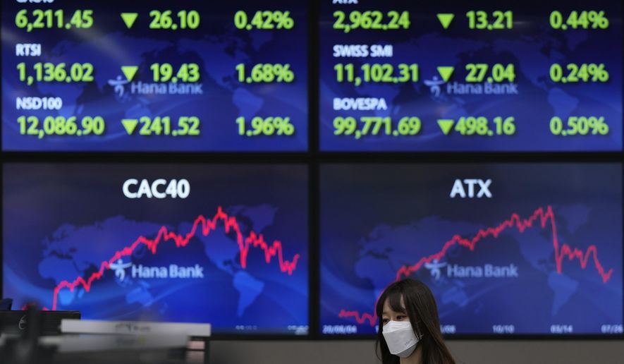 A currency trader walks near the screens at a foreign exchange dealing room in Seoul, South Korea, Wednesday, July 27, 2022. Asian stock markets followed Wall Street lower Wednesday as traders prepared for a possible sharp interest rate hike from the Federal Reserve to cool inflation. (AP Photo/Lee Jin-man)
