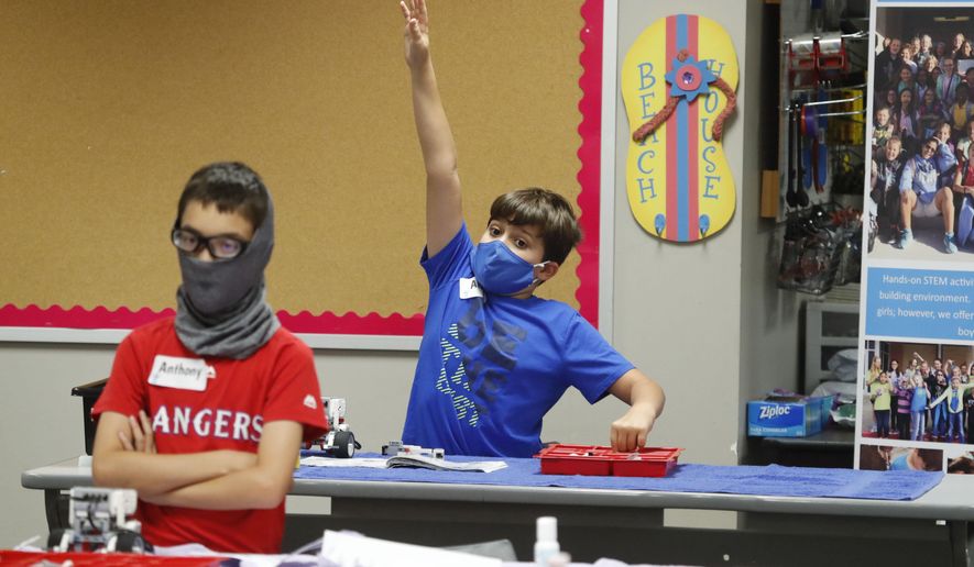 Aiden Trabucco, right, wears a mask as he raises his hand to answer a question behind Anthony Gonzales during a summer STEM camp at Wylie High School in Wylie, Texas, on July 14, 2020. Texas Gov. Greg Abbott’s executive order that forbids school districts from imposing mask mandates on schools to prevent the spread of COVID-19 was upheld Monday, July 25, 2022, by a divided federal appeals court panel in New Orleans. (AP Photo/LM Otero, File)