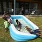 Jalen Askari, 7, right, plugs his nose as he falls into the pool he is playing in with his siblings, from left, Amari, 5, Bella, 2, and DJ, 10, in Portland, Ore., Tuesday, July 26, 2022. Temperatures are expected to top 100 degrees F (37.8 C) on Tuesday and wide swaths of western Oregon and Washington are predicted to be well above historic averages throughout the week. (AP Photo/Craig Mitchelldyer)