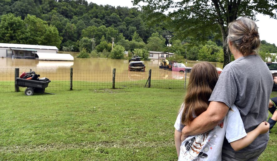 Bonnie Combs, right, hugs her 10-year-old granddaughter Adelynn Bowling watches as her property becomes covered by the North Fork of the Kentucky River in Jackson, Ky., Thursday, July 28, 2022. Flash flooding and mudslides were reported across the mountainous region of eastern Kentucky, where thunderstorms have dumped several inches of rain over the past few days. (AP Photo/Timothy D. Easley)