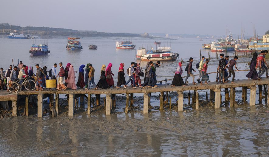 FILE - Workers walk to work at an export processing zone early in the morning after crossing the Mongla river in Mongla, Bangladesh, March 3, 2022. This Bangladeshi town stands alone to offer new life to thousands of climate migrants. (AP Photo/Mahmud Hossain Opu, File)