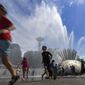 The International Fountain at Seattle Center is packed with children as they run from the water that is showering on them Wednesday, July 27, 2022 in Seattle. (Ellen M. Banner/The Seattle Times via AP)