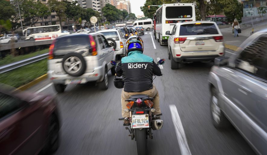 A Ridery app employee makes his way through traffic to pick up a customer, in Caracas, Venezuela, Wednesday, May 11, 2022. Ridery is one of at least three Venezuelan ride-sharing apps that launched during the pandemic — and which have taken advantage of a de facto switch of currencies from the Venezuelan bolivar to the U.S. dollar. (AP Photo/Matias Delacroix)