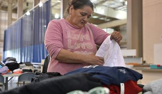 Evelyn Smith of Cary, Ky., gathers clothing at the Knott County Sportsplex in Leburn, Ky., Friday, July 29, 2022. Smith lost everything as fast rising floodwaters forced her from her home, and the sportsplex is being used as a evacuation center. (AP Photo/Timothy D. Easley)