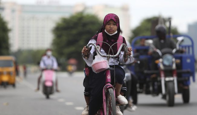 A girl rides her bicycle to school in Phnom Penh, Cambodia, Tuesday, Aug. 2, 2022. (AP Photo/Heng Sinith)
