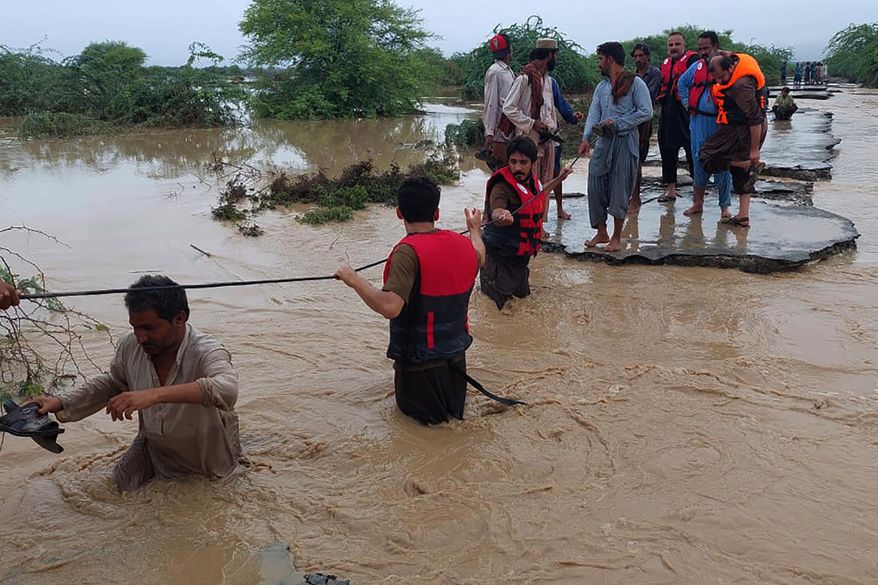 Rescue workers help villagers evacuate from flooded after heavy rains, in Lasbella, a district in Pakistan's southwest Baluchistan province, July 26, 2022. Pakistani search teams found the wreckage of a helicopter that went down Monday, Aug. 1. 2022, in the country’s flood-stricken southwest, killing an army general and five others on board, the military said Tuesday. The helicopter was part of aid efforts in the flood-affected Baluchistan, where rains and flash floods since June have killed nearly 150 people. (AP Photo/Hamdan Khan, File)