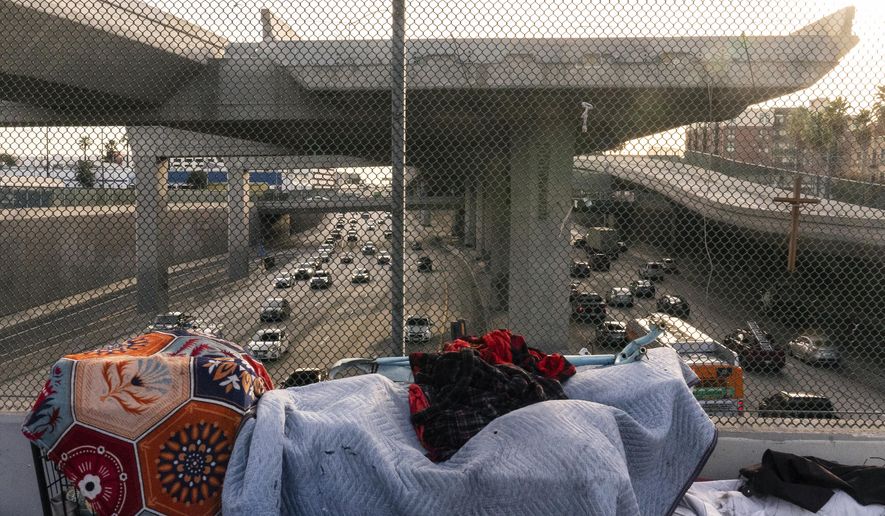 A homeless encampment is seen on a bridge over the CA-110 freeway, Wednesday, Dec. 15, 2021, in Los Angeles. The Los Angeles City Council has voted to ban homeless encampments within 500 feet of schools and daycare centers. The council voted Tuesday, Aug. 2, 2022, to broaden an existing ban on sleeping or camping near the facilities. (AP Photo/Damian Dovarganes,File)