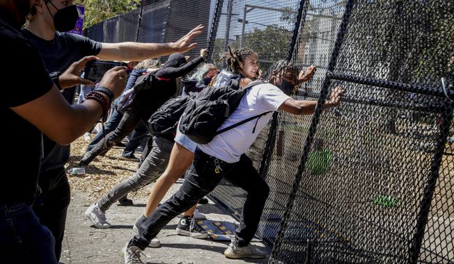 Protesters attempt to push down a gate surrounding People&#x27;s Park in Berkeley, Calif. on Wednesday, Aug. 3, 2022. Protesters gathered to decry the clearing out of the park in preparation for the development of student housing. (Brontë Wittpenn/San Francisco Chronicle via AP)