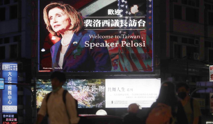 People walk past a billboard welcoming U.S. House Speaker Nancy Pelosi, in Taipei, Taiwan, Tuesday, Aug 2, 2022. Pelosi has arrived in Taiwan and becomes the highest-ranking American official in 25 years to visit the self-ruled island claimed by China, which quickly announced that it would conduct military maneuvers in retaliation for her presence.  (AP Photo/Chiang Ying-ying)