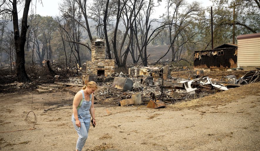 Sydney Corrales passes a lodge that burned during the McKinney Fire, Tuesday, Aug. 2, 2022, in Klamath National Forest, Calif. (AP Photo/Noah Berger)