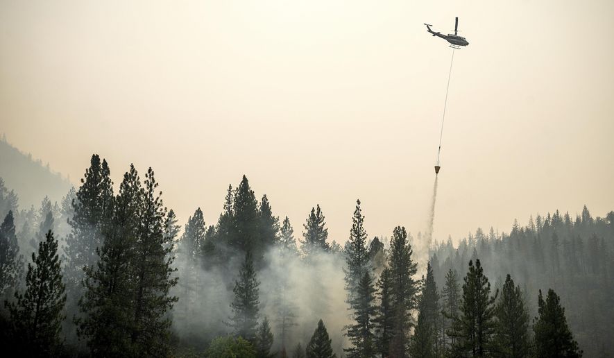 A helicopter drops water on a hot spot while battling the McKinney Fire on Tuesday, Aug. 2, 2022, in Klamath National Forest, Calif. (AP Photo/Noah Berger)