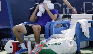 Taylor Fritz, of the United States, wraps his head is ice-cold towels between sets during a match against Daniel Evans, of Britain, at the Citi Open tennis tournament in Washington, Thursday, Aug. 4, 2022. (AP Photo/Carolyn Kaster)