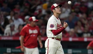 Los Angeles Angels starting pitcher Shohei Ohtani tosses the baseball in the air before being taken out of the game by manager Phil Nevin, background left, during the sixth inning against the Oakland Athletics on Wednesday, Aug. 3, 2022, in Anaheim, Calif. (AP Photo/Marcio Jose Sanchez)