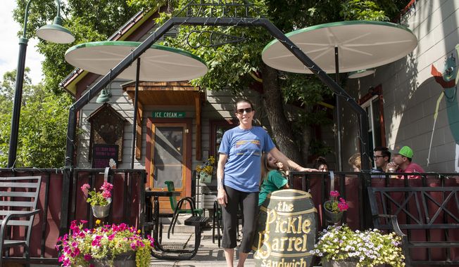 Owner of the Pickle Barrel, a Bozeman, Mont., sandwich shop, Jenny O&#x27;Brien stands next to the newly recovered Pickle Barrel sign on Monday, Aug. 1, 2022. The sign was stolen 20 years ago and returned Monday, Aug. 1. (Rachel Leathe/Bozeman Daily Chronicle via AP)