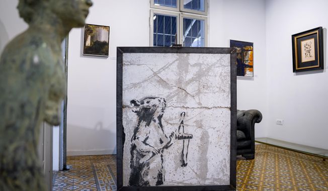 A painting by the secretive British graffiti artist Banksy that was mysteriously transferred from the occupied West Bank is revealed in Urban Gallery in Tel Aviv, Israel, Thursday, Aug. 4, 2022. The painting of a slingshot-toting rat once stood near Israel&#x27;s separation barrier and was one of several works created in 2007 that protest Israel&#x27;s decades-long occupation of territories the Palestinians want for a future state. (AP Photo/Oded Balilty)