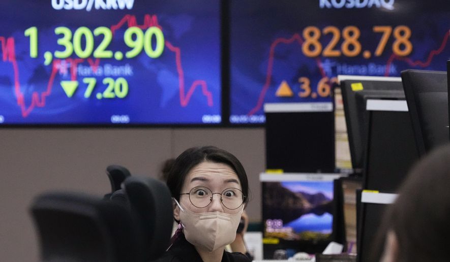 A currency trader talks with her colleague at the foreign exchange dealing room of the KEB Hana Bank headquarters in Seoul, South Korea, Friday, Aug. 5, 2022. Asian stock markets rose Friday ahead of U.S. job market data that might influence Federal Reserve decisions about further interest rate hikes. (AP Photo/Ahn Young-joon)