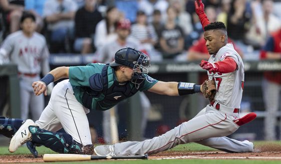 Seattle Mariners catcher Cal Raleigh tags out Los Angeles Angels&#39; Magneuris Sierra at home plate after Sierra attempted to stretch a triple to an inside-the-park home run during the second inning of a baseball game Friday, Aug. 5, 2022, in Seattle. (AP Photo/Stephen Brashear)