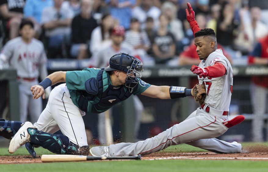 Seattle Mariners catcher Cal Raleigh tags out Los Angeles Angels&#39; Magneuris Sierra at home plate after Sierra attempted to stretch a triple to an inside-the-park home run during the second inning of a baseball game Friday, Aug. 5, 2022, in Seattle. (AP Photo/Stephen Brashear)