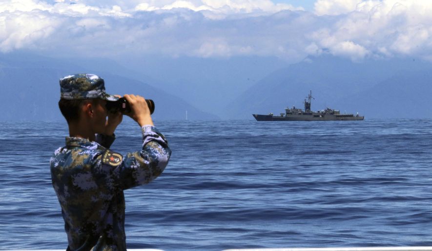 In this photo provided by China’s Xinhua News Agency, a People&#39;s Liberation Army member looks through binoculars during military exercises as Taiwan’s frigate Lan Yang is seen at the rear, on Friday, Aug. 5, 2022. China is holding drills in waters around Taiwan in response to a recent visit by U.S. House Speaker Nancy Pelosi. (Lin Jian/Xinhua via AP)