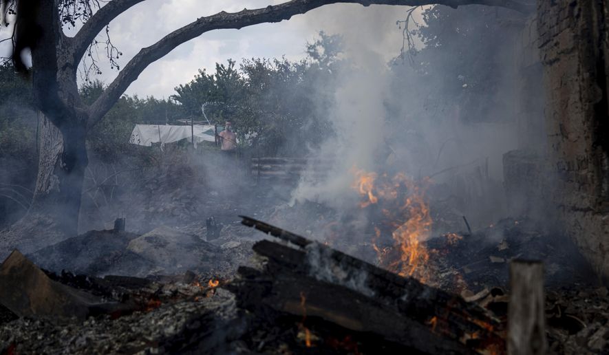 A local resident, back, tries to stop the fire at a neighbor&#x27;s house destroyed by a Russian attack in Mykolaiv, Ukraine, Friday, Aug. 5, 2022. (AP Photo/Evgeniy Maloletka)