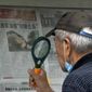 A man uses a magnifying glass to read a newspaper headline reporting on Chinese People&#39;s Liberation Army (PLA) conducting military exercises, at a stand in Beijing, Sunday, Aug. 7, 2022. U.S. Secretary of State Antony Blinken said Saturday that China should not hold hostage talks on important global matters such as the climate crisis, after Beijing cut off contacts with Washington in retaliation for U.S. House Speaker Nancy Pelosi&#39;s visit to Taiwan earlier this week. (AP Photo/Andy Wong)