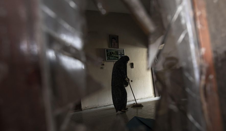 A Palestinian woman cleans her damaged house following an Israeli airstrike in Rafah, southern Gaza strip, Sunday, Aug. 7, 2022. Israel has killed two senior Islamic Jihad militants in three days of air strikes in the Gaza Strip, and Palestinian militants have launched nearly 600 rockets at Israel. Palestinian officials say at least 31 people in Gaza have died. (AP Photo/Fatima Shbair)