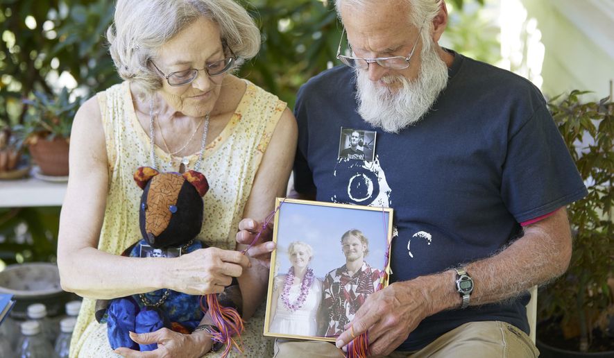 George, right, and Carolyn Spaulding hold an old family photo showing their son, Brian, in Portland, Ore., Wednesday, July 20, 2022. Five years after Brian&#39;s parents found him fatally shot in the home he shared with roommates, his slaying remains a mystery that seems increasingly unlikely to be solved as Portland police confront a spike in killings and more than 100 officer vacancies. (AP Photo/Craig Mitchelldyer)