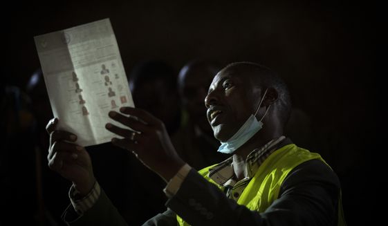 An election official holds up ballots for other officials and party agents to see, as they start to count votes at a polling station in Olepolos Primary School, in Kajiado County, Kenya Tuesday, Aug. 9, 2022. Polls opened Tuesday in Kenya&#39;s unusual presidential election, where a longtime opposition leader who is backed by the outgoing president faces the deputy president who styles himself as the outsider. (AP Photo/Ben Curtis)