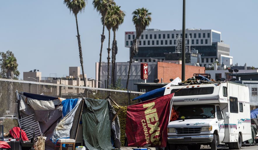 Homeless encampments block the street on an overpass of the Hollywood freeway in Los Angeles, on July 7, 2021. The Los Angeles City Council has voted to ban homeless encampments within 500 feet of schools and daycare centers. The council voted Tuesday, Aug. 9, 2022, to broaden an existing ban on sleeping or camping near the facilities. (AP Photo/Damian Dovarganes, File)