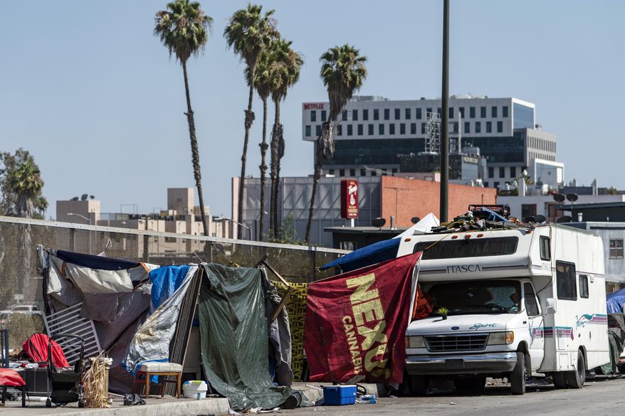 Homeless encampments block the street on an overpass of the Hollywood freeway in Los Angeles, on July 7, 2021. The Los Angeles City Council has voted to ban homeless encampments within 500 feet of schools and daycare centers. The council voted Tuesday, Aug. 9, 2022, to broaden an existing ban on sleeping or camping near the facilities. (AP Photo/Damian Dovarganes, File)