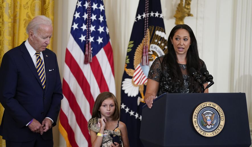 Danielle Robinson, wife of Sgt. 1st Class Heath Robinson, who died of cancer two years ago, speaks as her daughter Brielle Robinson and President Joe Biden listen during a ceremony in the East Room of the White House, Wednesday, Aug. 10, 2022, in Washington. During the event Biden signed veterans health care legislation that ends a long battle to expand benefits for people who served near burn pits. (AP Photo/Evan Vucci)