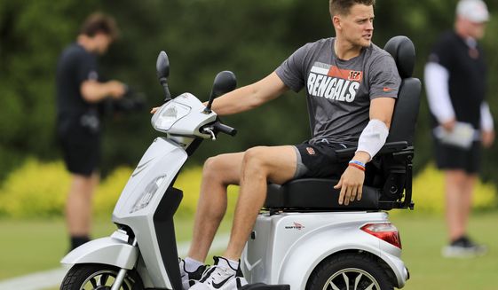 Cincinnati Bengals&#39; Joe Burrow sits on a scooter as he watches during the NFL football team&#39;s training camp in Cincinnati, Monday, Aug. 1, 2022. (AP Photo/Aaron Doster)