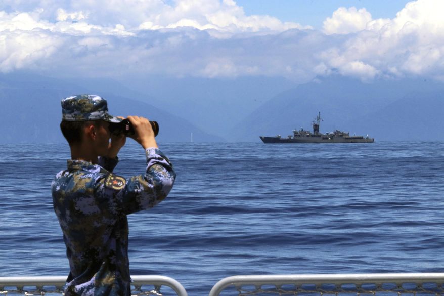 In this photo provided by China&#39;s Xinhua News Agency, a People&#39;s Liberation Army member looks through binoculars during military exercises as Taiwan&#39;s frigate Lan Yang is seen at the rear on Aug. 5, 2022. China on Wednesday, Aug. 10, reaffirmed its threat to use military force to bring self-governing Taiwan under its control, amid threatening Chinese military exercises that have raised tensions between the sides to their highest level in years. (Lin Jian/Xinhua via AP, File)
