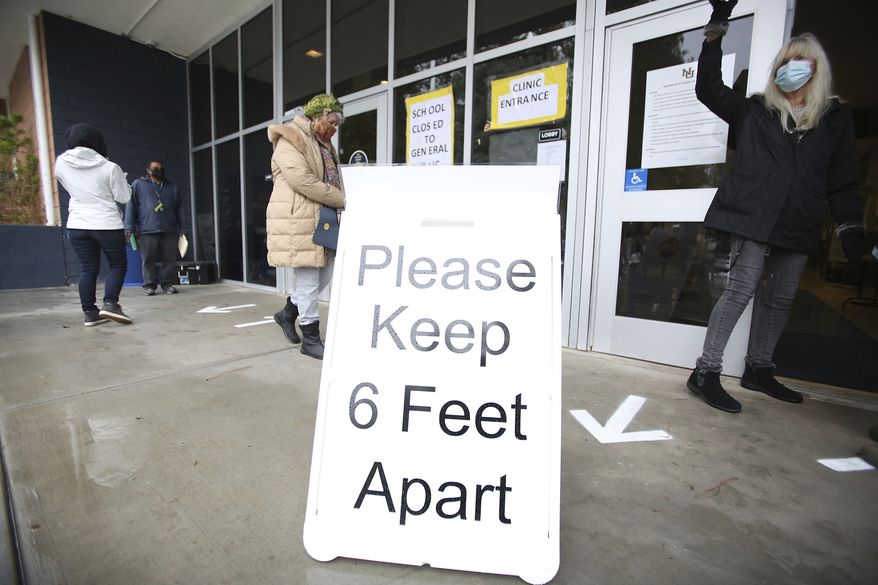 FILE - A sign asks those getting vaccinated to keep 6 feet apart during the vaccination event, Wednesday, Jan. 27, 2021, at Nevada Union High School in Grass Valley, Calif. The CDC has again revised its COVID guidelines, further relaxing quarantine recommendations and dropping the recommendation that people stay at least 6 feet away from each other. (Elias Funez/The Union via AP, File)