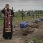 A priest prays for unidentified civilians killed by Russian troops during Russian occupation in Bucha, on the outskirts of Kyiv, Ukraine, Thursday, Aug. 11, 2022. Eleven unidentified bodies exhumed from a mass grave were buried in Bucha Thursday (AP Photo/Efrem Lukatsky)