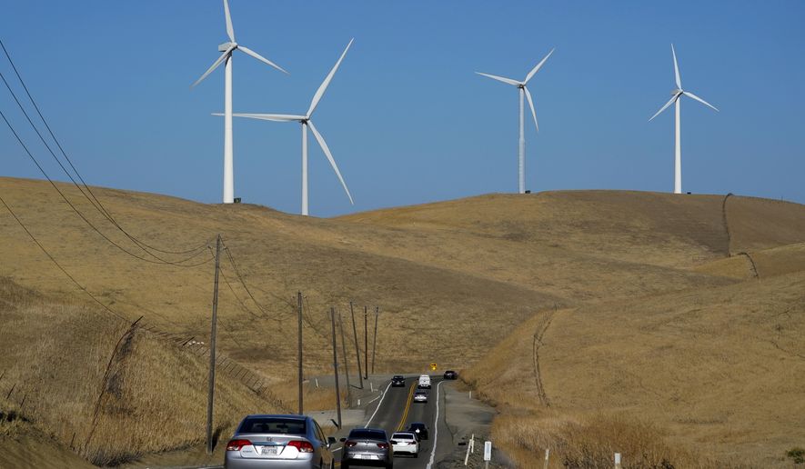 Vehicles move down Altamont Pass Road with wind turbines in the background in Livermore, Calif., Wednesday, Aug. 10, 2022. Congress is poised to pass a transformative climate change bill on Friday, Aug. 12. The crux of the long-delayed bill is to use incentives to accelerate the expansion of clean energy such as wind and solar power, speeding the transition away from the oil, coal and gas that largely cause climate change. (AP Photo/Godofredo A. Vásquez)