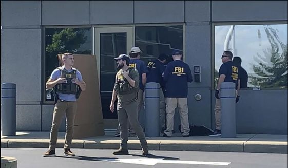 In this image taken from FOX19 Cincinnati video, FBI officials gather outside the FBI building in Cincinnati, Thursday, Aug. 11, 2022. An armed man decked out in body armor tried to breach a security screening area at the FBI field office in Ohio on Thursday, then fled and exchanged gunfire in a standoff with law enforcement, authorities said. (FOX19 Cincinnati via AP) ** FILE **