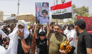 Supporters of the Shiite cleric Muqtada al-Sadr hold prayer near the parliament building in Baghdad, Iraq, Friday, Aug. 12, 2022. Al-Sadr&#39;s supporters continue their sit-in outside the parliament to demand early elections. The photo show Muqtada al-Sadr and his late father Muhammed Sadiq al-Sadr. (AP Photo/Anmar Khalil)