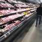 In this May 10, 2020 file photo, a shopper pushes his cart past a display of packaged meat in a grocery store in southeast Denver. Prices at the wholesale level fell from June to July, the first month-to-month drop in more than two years and a sign that some of the U.S. economy&#39;s inflationary pressures cooled last month. Thursday’s report from the Labor Department showed that the producer price index — which measures inflation before it reaches consumers — declined 0.5% in July. (AP Photo/David Zalubowski, File)