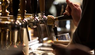 Closeup of a bartender pouring a dark stout beer at a pub. (Shutterstock/IsabellaO)
