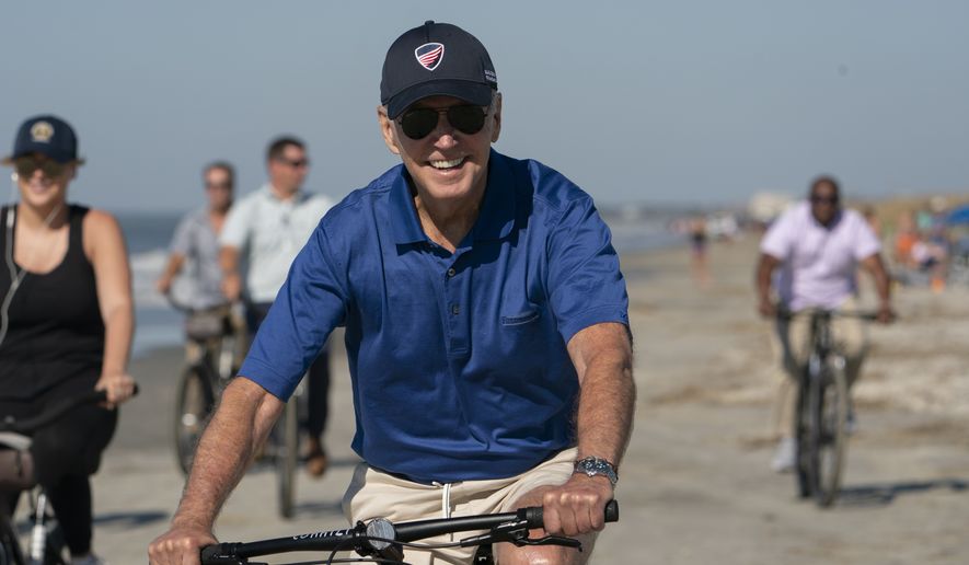 President Joe Biden rides a bicycle along the beach at Kiawah Island, S.C., Sunday, Aug. 14, 2022. Biden is in Kiawah Island with his family on vacation. (AP Photo/Manuel Balce Ceneta)