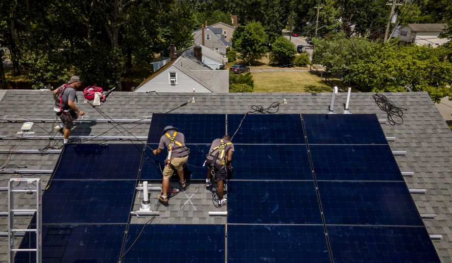 Employees of N.Y. State Solar, a residential and commercial photovoltaic systems company, install an array of solar panels on a roof, Thursday, Aug. 11, 2022, in the Long Island hamlet of Massapequa, N.Y. Americans are less concerned now about how climate change might impact them personally — and about how their personal choices affect the climate than they were three years ago, according to a according to a June poll from The Associated Press-NORC Center for Public Affairs Research.  (AP Photo/John Minchillo, File)