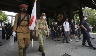 Visitors in old Japanese Imperial army uniforms enter Yasukuni Shrine, which honors Japan&#39;s war dead, Monday, Aug. 15, 2022, in Tokyo. Japan marked the 77th anniversary of its World War II defeat Monday. (AP Photo/Eugene Hoshiko)