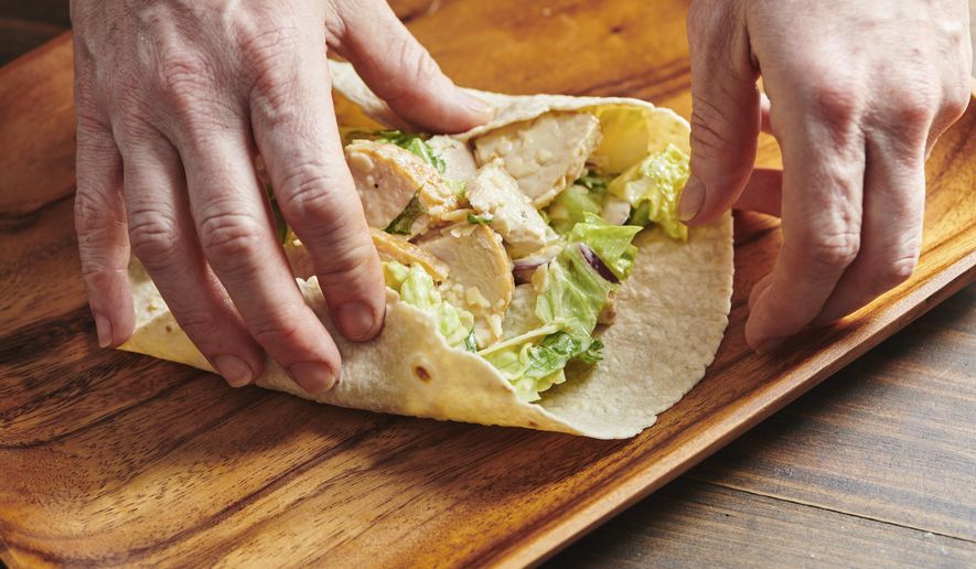 These photos show a recipe for chicken caesar wrap in New York in March 2019. There is little debate that the sandwich is the mainstay of most kids’ lunches but wraps have also taken their place in the pantheon of sandwich possibilities. (Cheyenne Cohen via AP)