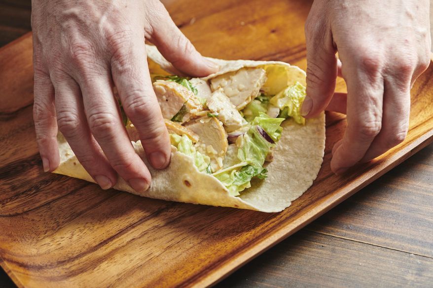 These photos show a recipe for chicken caesar wrap in New York in March 2019. There is little debate that the sandwich is the mainstay of most kids’ lunches but wraps have also taken their place in the pantheon of sandwich possibilities. (Cheyenne Cohen via AP)