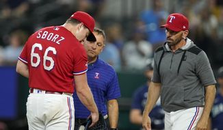 Texas Rangers starting pitcher Josh Sborz (66) is checked on by athletic trainer Matt Lucero, center, and manager Chris Woodward after Sborz was struck by the ball on a single by Seattle Mariners&#39; Mitch Haniger during the first inning of a baseball game in Arlington, Texas, Friday, Aug. 12, 2022. (AP Photo/Tony Gutierrez) **FILE**