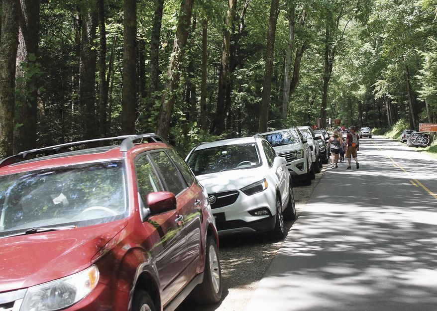 Visitors walk down Laurel Creek Road to Cades Cove after parking along the road because parking lots around the Cove were full, on June 24, 2020, in The Great Smoky Mountains National Park. Beginning March 2023, visitors to Great Smoky Mountains National Park will need to purchase a parking pass to use the facilities. (Tom Sherlin/The Daily Times via AP, File)